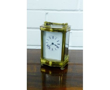 A French brass cased carriage clock with glass panels, a white enamel dial and Roman numerals on four turned feet, carry hand