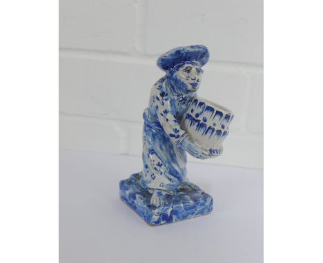 An 19th century tin glazed blue and white monkey figure, modelled standing holding a barrel on a square plinth base, 14cm hig