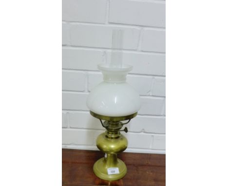 A brass oil lamp with white opaque glass shade