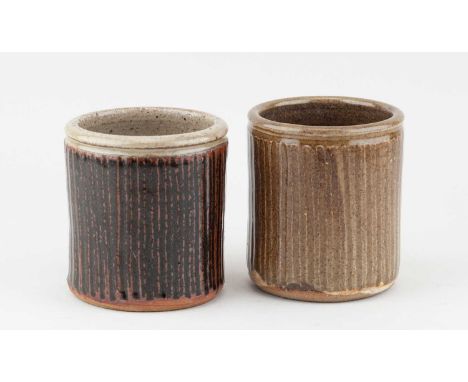 JIM MALONE (born 1946); a near pair of fluted stoneware utensil pots covered in tenmoku breaking to kaki glaze and green ash 