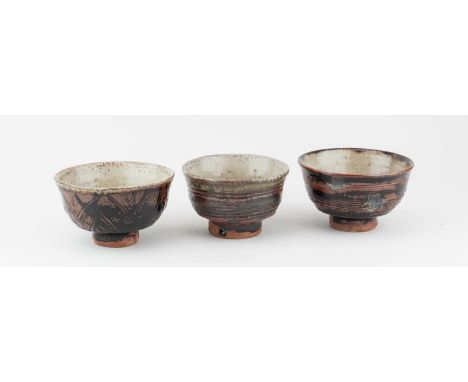 JIM MALONE (born 1946); a trio of stoneware chawan covered in tenmoku breaking to kaki glaze with combed, impressed and incis