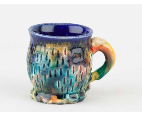 † KATE MALONE (born 1959); a small earthenware cup covered in polychrome glaze, impressed KM mark, height 6.5cm.   Condition 