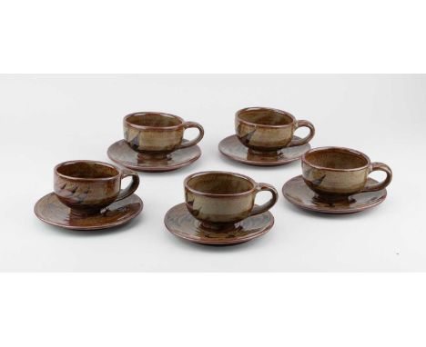 Abuja Pottery; a group of five stoneware cups and saucers covered in oatmeal and iron glaze with kaki decoration, impressed p