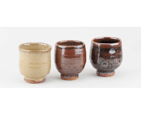 JIM MALONE (born 1946); a trio of stoneware yunomi covered in tenmoku breaking to kaki glaze and nuka glaze with impressed de