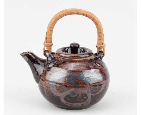 † JOHN MALTBY (1936-2020) for Stoneshill Pottery; a stoneware teapot with cane handle covered in tenmoku breaking to kaki gla