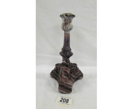 A Victorian pressed purple candlestick on three feet, each with the face of some creature, 21 cm tall.