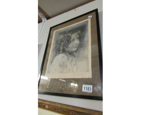 A framed and glazed portrait of a child, signed but indistinct.