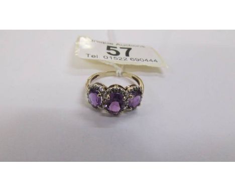 A 3 stone diamond and amethyst ring in a cluster style, deep colour amethyst in a gold tested shank. Size P. ****Condition re