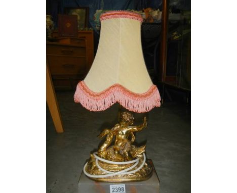 A gilded table lamp surmounted cherub on alabaster base.