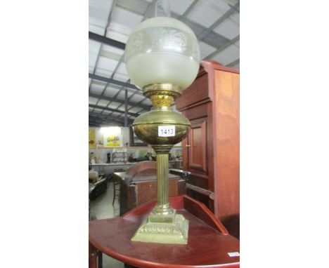 A brass oil lamp with shade and chimney.