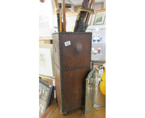 A leather covered stick stand with walking sticks and umbrella.