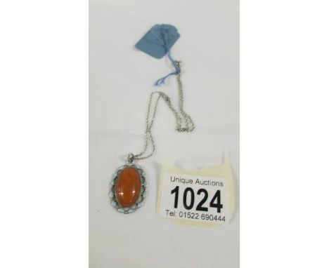 An amber vintage pendant in a pale blue enamel surround with an attached silver chain,