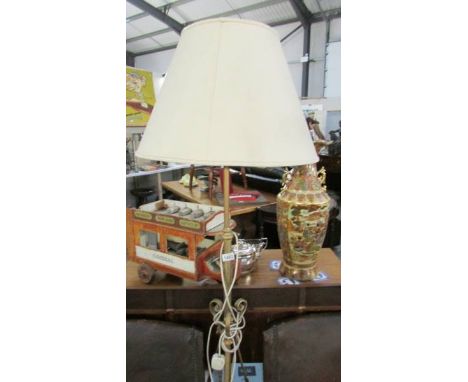 A wrought iron standard lamp with shade.