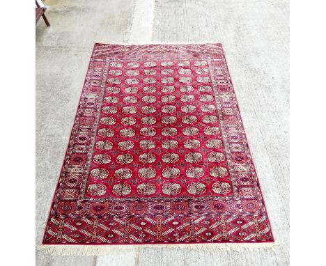 Vintage machine made wool Bokhara rug having six rows of twelve medallions. 248cm x 344cm.