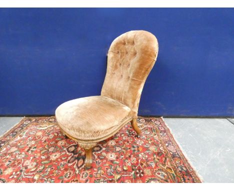 Victorian button back nursing chair in beige velvet upholstery, raised on cabriole supports. Height 87cm.