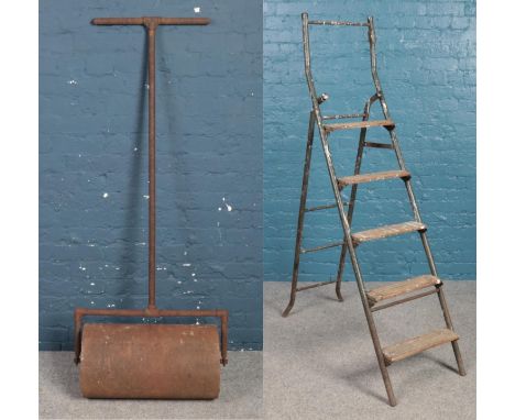A vintage cast iron garden roller along with a set of vintage shop ladders. Roller 58cm wide.  