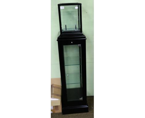 A modern glass mantel clock on a pedestal display case 
