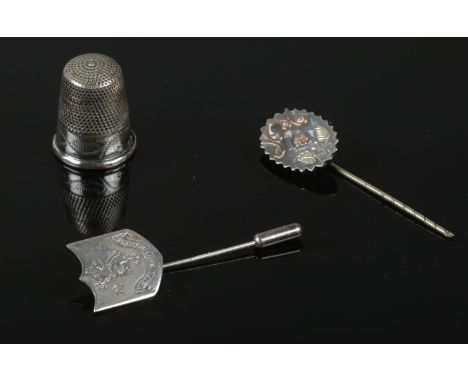 A silver thimble and stick pin along with a white metal stick pin.  