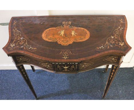 A French style inlaid mahogany card / games table with serpentine fold-over top inlaid with putti playing with hoops and scro