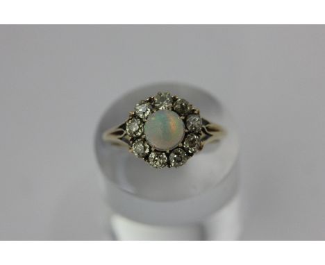 An opal and diamond cluster ring within a border of eight old cut diamonds, with one simulant