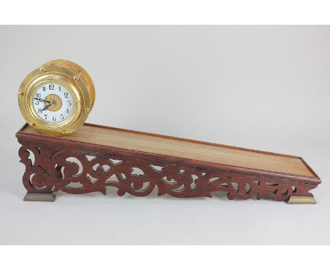 A gilt metal rolling clock with 8cm white enamel dial and Arabic numerals, in drum shaped case with applied cast foliate deco