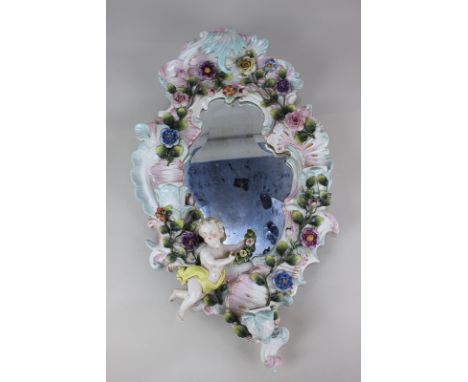 A Dresden porcelain wall mirror with applied floral decoration and putti holding a spray of flowers, with three candle sconce