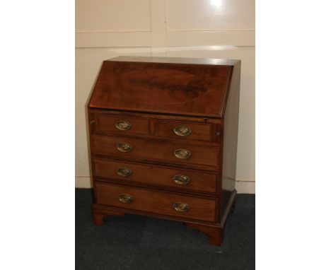 An Edwardian mahogany inlaid bureau, the fall with oval flame veneered panel enclosing fitted interior, above two short over 