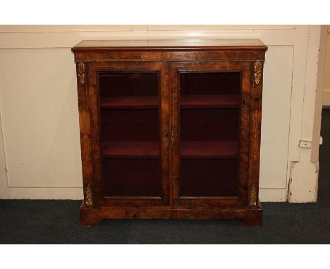 A Victorian inlaid walnut gilt metal mounted pier cabinet with two glazed panel doors enclosing velvet lined interior and two