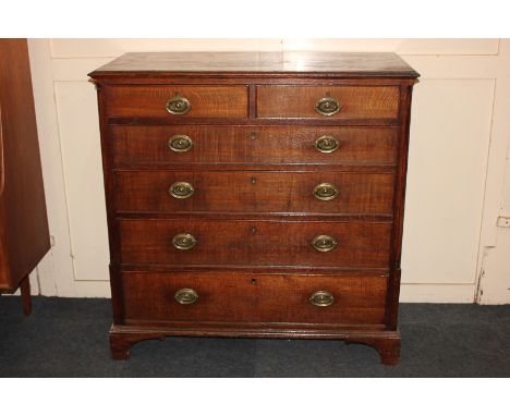 A George III oak chest of two short over four long drawers, with brass drop handles and oval embossed back plates between col