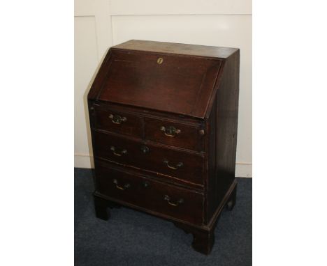 A George III small oak bureau with fall enclosing pigeon holes and small drawers over two short and two  long drawers (a/f), 