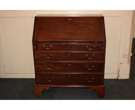 A George III mahogany bureau, the fall enclosing a fitted interior above four graduated drawers with brass drop handles, on b