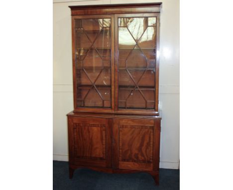 A 19th century mahogany bookcase with two glazed panel doors enclosing four shelves, the later cupboard base with two panel d