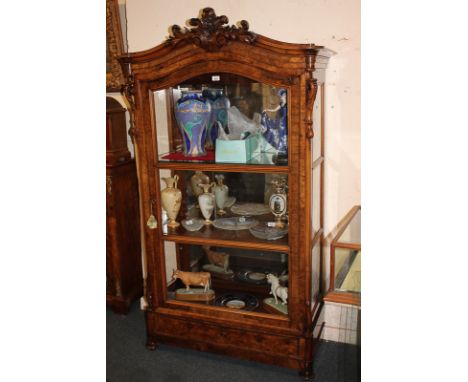 A Victorian walnut display cabinet with scrolling foliate carved surmount and pierced sides, large panel glazed door enclosin