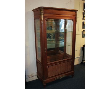 A French style gilt metal mounted display cabinet with glazed panel door enclosing two glass shelves with mirror back, on flu