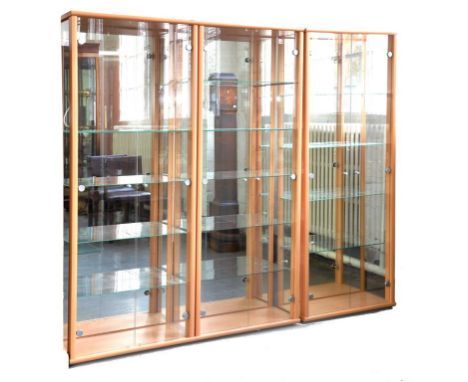 A SET OF THREE CONTEMPORARY LIGHT LAMINATE DISPLAY CABINETS WITH GLASS FULL LENGTH DOORS, 66CM W