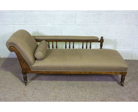 An Edwardian chaise longue, with walnut turned feet and bobbin turned back supports, currently upholstered in green fish-scal