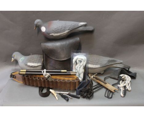 A box lot containing three pigeon decoys, various dog whistles, vintage shotgun cleaning rods etc.