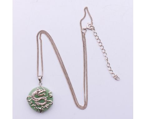 A silver dragon motif and jade pendant on a silver chain.  Pendant 2 cm diameter, chain 44 cm long.   