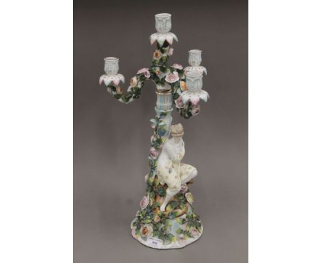 A 19th century Continental florally-encrusted figural three-branch porcelain candelabra. 50 cm high.