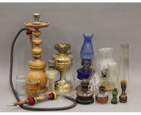 A wooden hookah pipe and a quantity of oil lamps and chimneys. The former approximately 60 cm high.