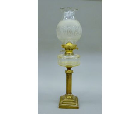 A brass and glass oil lamp with shade. 69 cm high.
