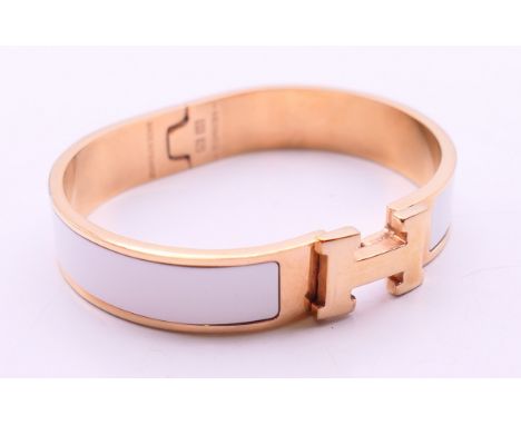 A Hermes Paris white enamel gold plated Clic H bracelet, in a Hermes box.  6.5 cm diameter, 12 mm high.