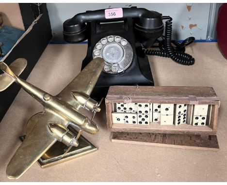 A brass aeroplane desk weight, a vintage Bakelite rotary telephone and a set of dominoes 