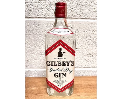 A vintage, probably 1980's, 70cl bottle of Gilbey's London Dry Gin, 43% proof, paper cap label, slight tears but intact, back