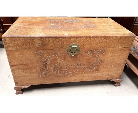An oriental light camphorwood chest with carved decoration to the front 