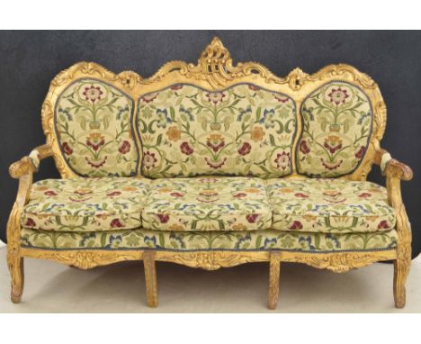 Decorative large gilt settee, the scrolling shaped and upholstered back over scroll arms and cushion seat, raised on six legs