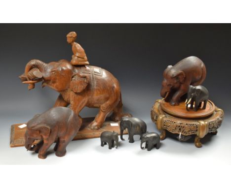 Treen - a carved wooden elephant, trunk erect, carrying a branch; others smaller; a carved Japanese hardwood stand (8)