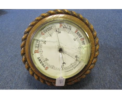 An aneroid barometer in rope-effect in oak mount, 28cm wide (af)