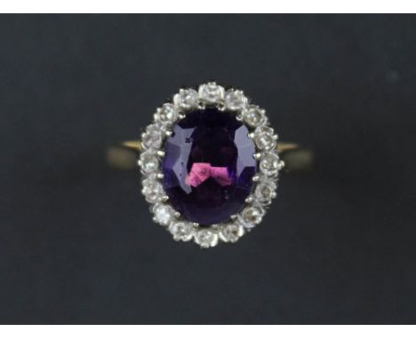 Yellow metal ring stamped 18ct. set with large Amethyst surrounded by 16 diamonds size N weight 5.5 grams