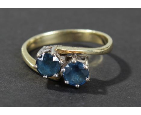 Gold and platinum blue sapphire set crossover ring, the platinum head set with two brilliant cut blue sapphires, ring size K,